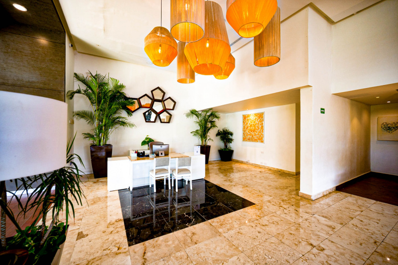 The reception desk is in a large, step-free area. The reception desk is low and has 2 chairs in front of  it.