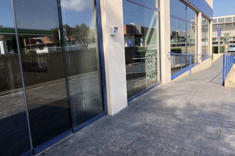 Access to the hotel is through a sliding glass door. There is a paved ramp with handrails leading to a parking area.