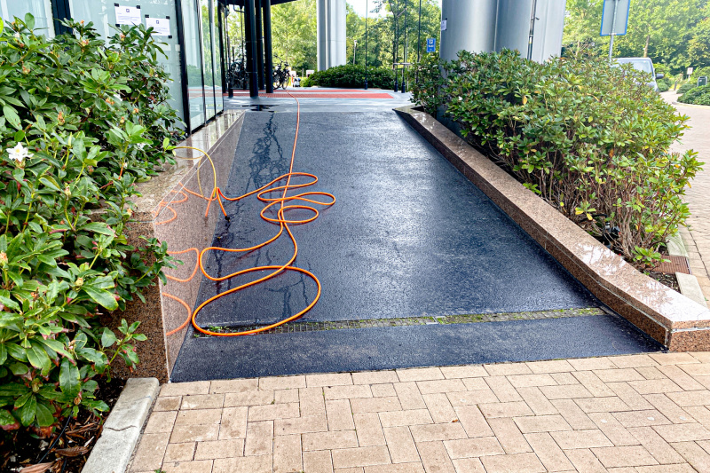 There is a wide ramp leading from a brick-paved walkway up to the covered hotel entrance. There are no handrails.