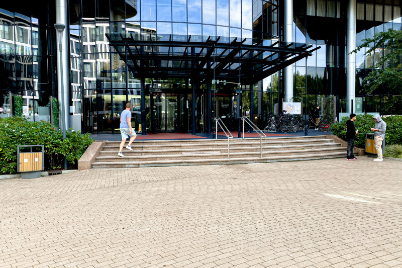 A flight of 5 broad steps with central handrails leads up to the hotel entrance. Access is through revolving doors