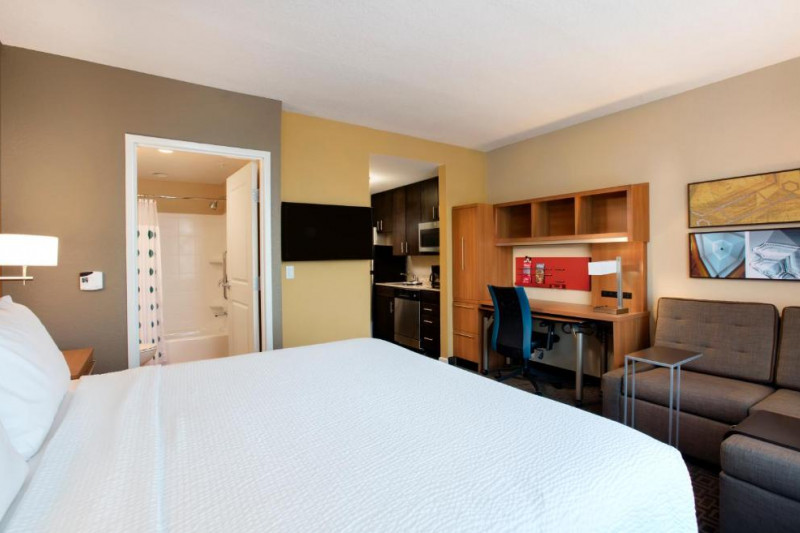 The room has one king-sized bed with nightstands, a workstation, a chair, and a sofa-bed. Leading of from the room is the ensuite with a bathtub and a kitchen area. There is a wall-mounted TV.