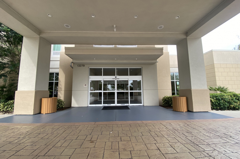 Access to the hotel is from a step-free, paved area. There is a set of automatic, sliding glass doors.