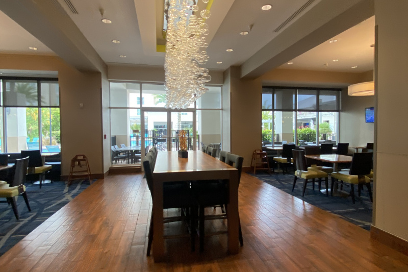 The spacious, step-free dining area has wooden flooring with a table and chairs in the center of the room. There is also a carpeted area with assorted tables and movable chairs.