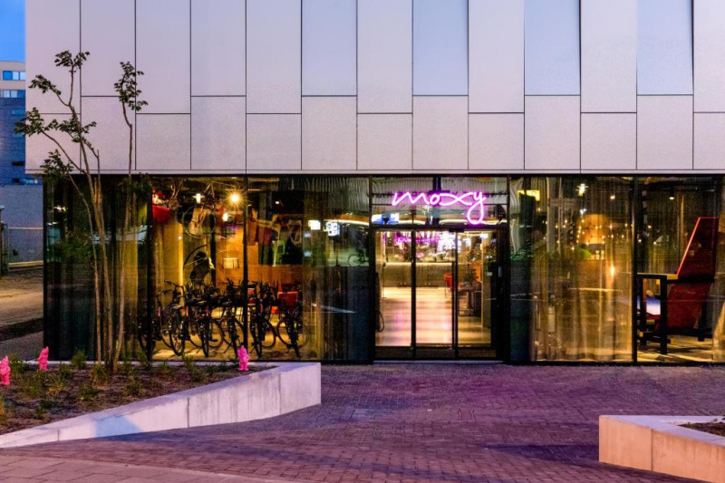 A brick-paved sloping area leads to the hotel entrance. Access is through 2 glass sliding doors.