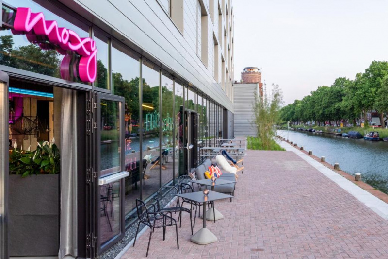 The outdoor seating area is on the riverside. It has assorted tables and movable chairs.