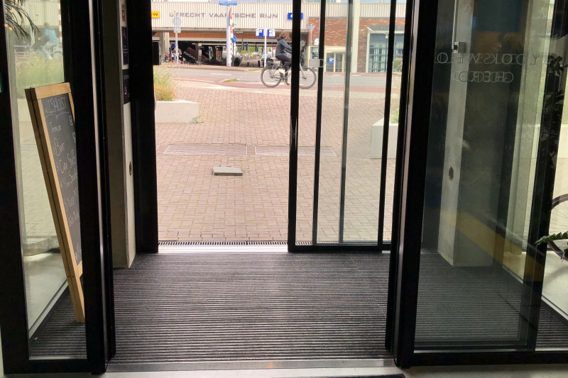 Two sets of glass sliding doors provide step-free access to the brick-paved sidewalk.