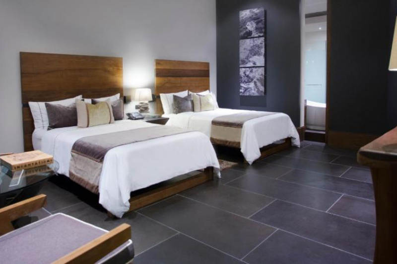 The spacious room has 2 queen-sized beds with a central nightstand. There are 2 padded chairs and a small round table. There is plenty of floor space.