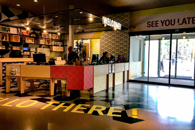 The spacious reception area has a high check-in desk. There are sliding doors providing step-free access to the sidewalk.