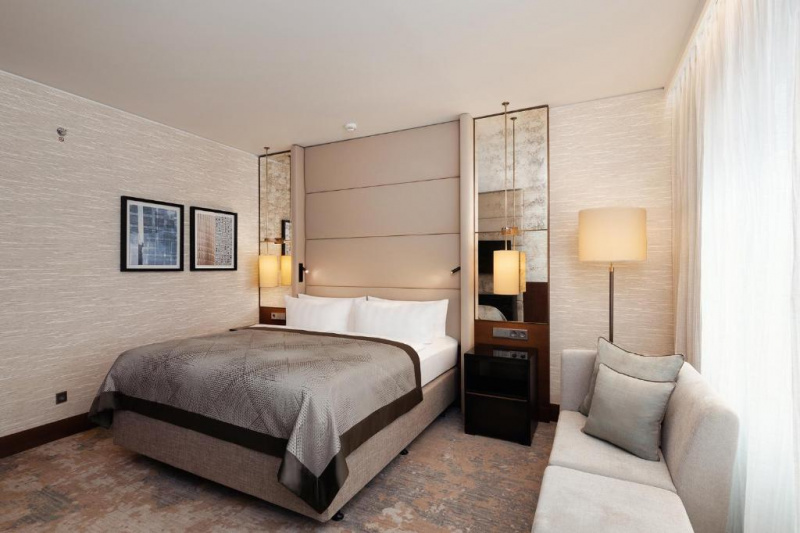 This hotel room has a double bed with nightstands. There is a sofa along one wall. There is adequate floorspace.