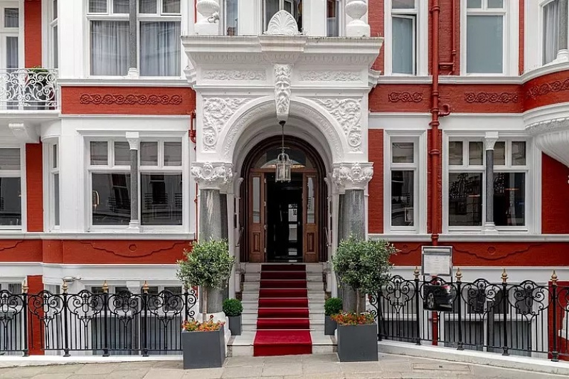 Exterior view of the hotel portico and entrance. A flight of 7 stone steps with handrails leads from the sidewalk to double wood and glass doors.