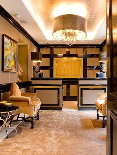 The reception area has 2 high check-in desks. There are 2 large armchairs with a side table in front of the check-in desks.