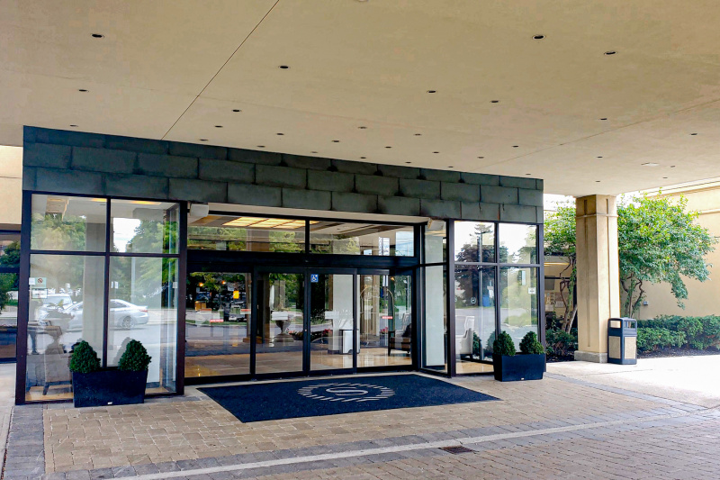 The hotel entrance has a dropped curb. There are large automatic glass doors leading to the lobby.