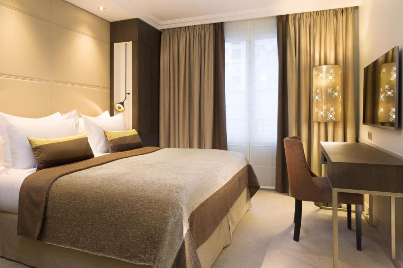 This carpeted room has a king-sized bed. There is a workstation opposite it with a movable chair. Floor space is limited.