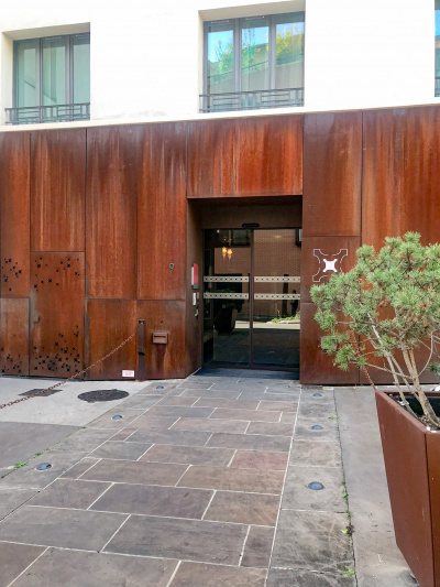 The entrance to the hotel is from a paved pathway. A set of automatic glass doors leads into the hotel.