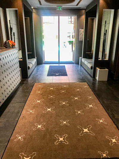 The hotel lobby is small and step-free. There are built-in sofas on either side of the walkway and a high reception desk.