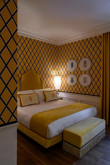 The room has parquet flooring, a queen-sized bed with nightstand and a plush bench at the foot of the bed.