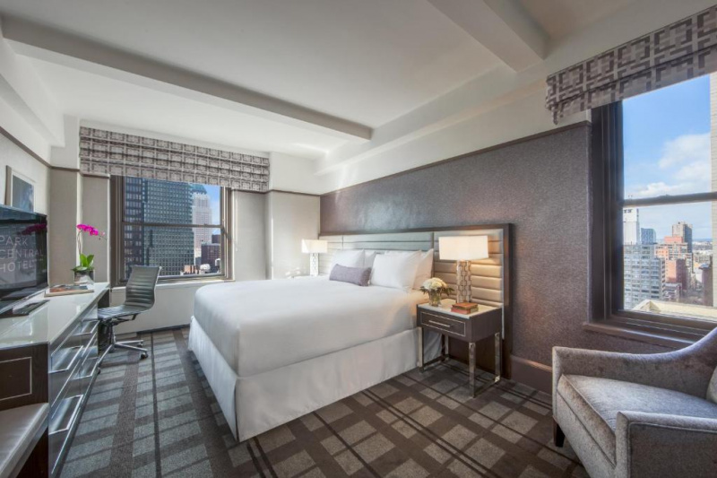 This room has a king-sized bed with nightstands. There is a workstation, a movable chair, a TV and an armchair. The room has city views.