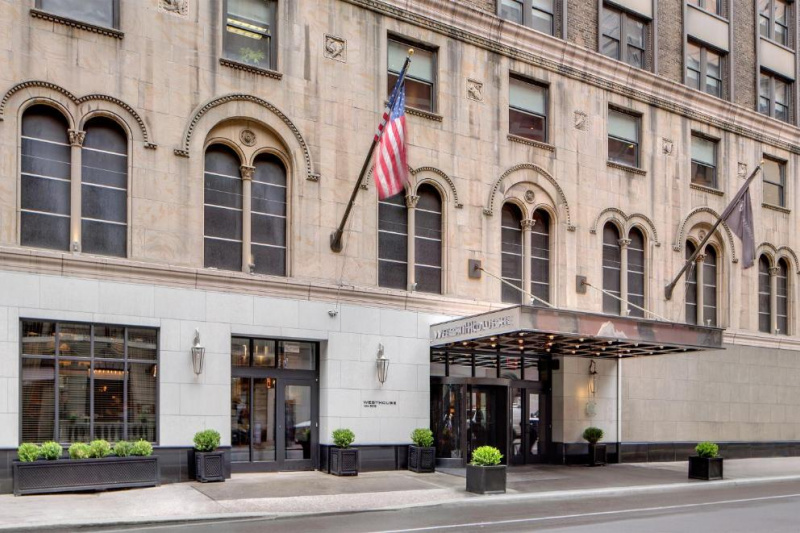 Exterior view of the hotel from the sidewalk. The main entrance has a canopy cover and a revolving door.