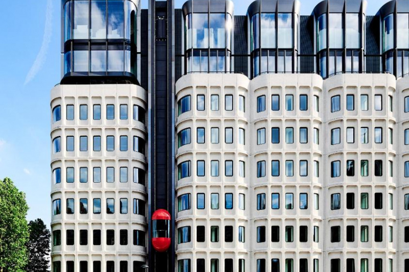 Exterior view of the hotel, which is a large, modern building. There is a red bubble elevator on its exterior.