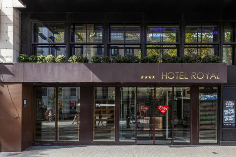 The hotel entrance is from a wide, paved sidewalk. There are automatic glass doors leading to the lobby.