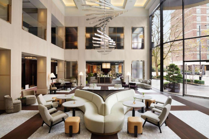 The spacious hotel lobby has several seating areas with a banquette seat, assorted sofas, armchairs, pouffes, and coffee tables.