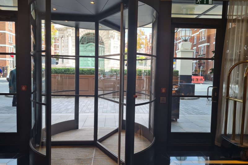The revolving door leads onto the paved sidewalk. There are glass doors to either side of it.