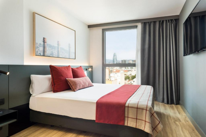 This small room has 1 full-sized bed with nightstands. There is a wall-mounted TV and a view of the city.
