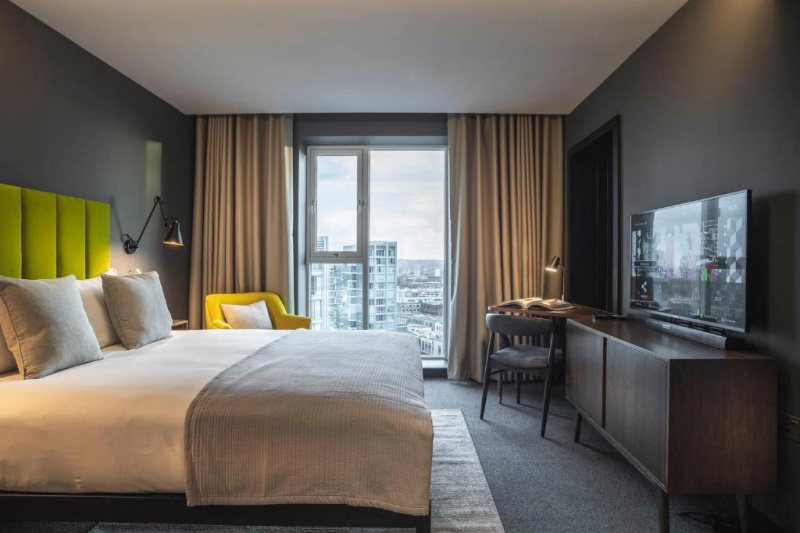 This room has 1 king-sized bed with nightstands, an armchair, a table and a movable chair. There is also a long cabinet with a TV.