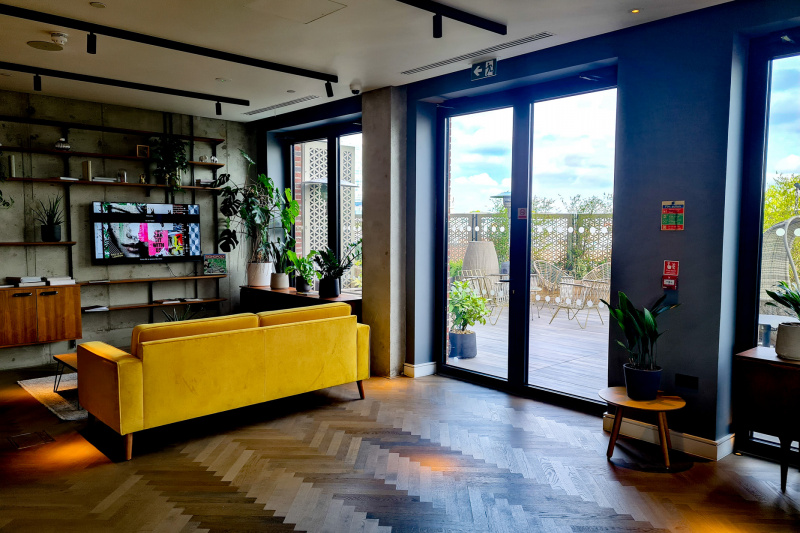 The spacious seating area has a sofa with a wall-mounted TV. There are French doors leading to an outdoor seating area.