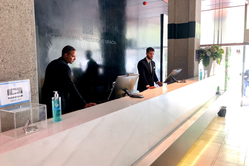 The reception desk i near the hotel entrance. It has a long high counter with a short lowered section and a low shelf running along the counter.