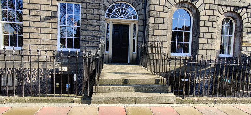 Access to the hotel is from the sidewalk. There are 3 high steps leading to a wooden door. There are no handrails.