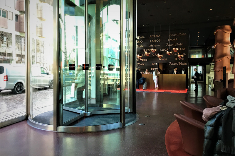 The revolving door leads to a spacious, step-free lobby. There is a reception desk with a high check-in counter and a seating area.