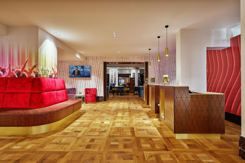 The spacious, step-free reception area has 3 check-in desks with high counters. In the center of the room, there is a circular sofa.