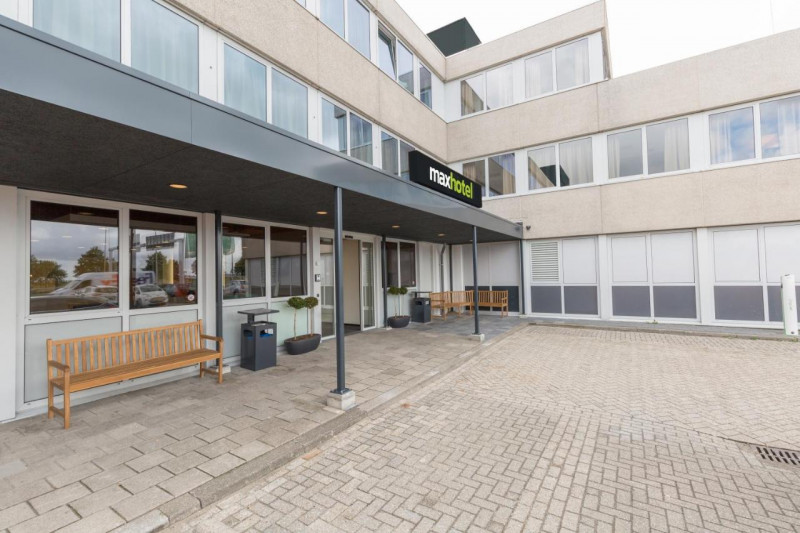Access to the hotel is through 2 glass sliding doors. There are wooden benches outside the hotel and a small curb onto the sidewalk.