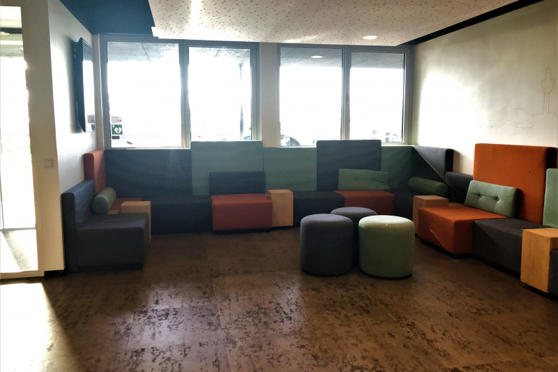 The spacious lobby has a seating area with pouffes in the center of the area.