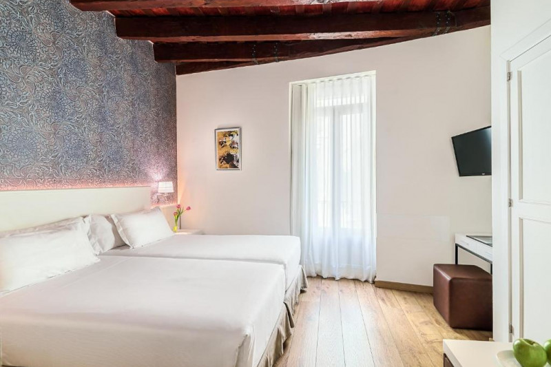 The spacious room has twin beds, a wall-mounted TV, a workstation and a pouffe.
