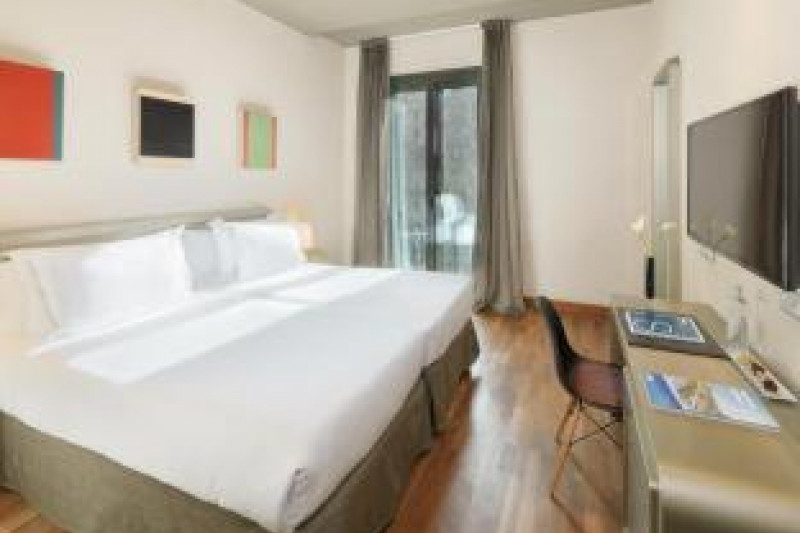 The room has twin beds with a workstation, a movable chair and a wall-mounted TV opposite the beds.