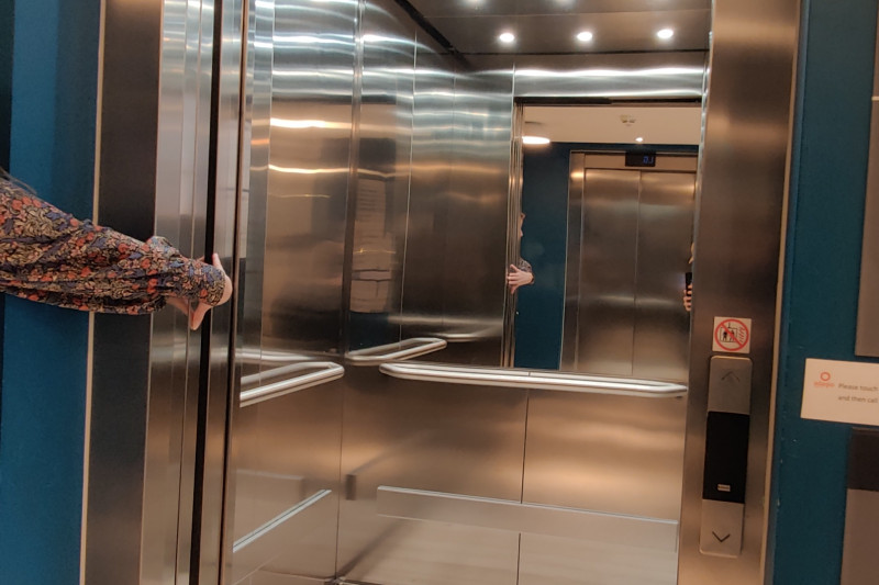 The elevator has accessible call buttons. There are handrails around the inside panels.