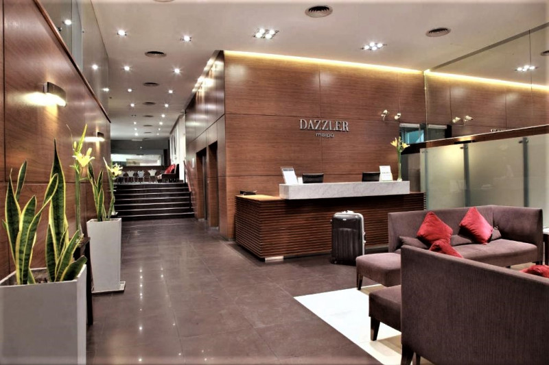 The spacious hotel reception has a high check-in desk with a lowered counter area. The are stairs with a handrail leading to another floor.