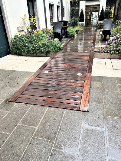 There is a long wooden ramp that leads up to the hotel entrance, which has 2 glass sliding doors. There are no handrails.