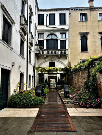 The outdoor wooden ramp leads up to the hotel entrance and has seating and plants on either side. There are no handrails.