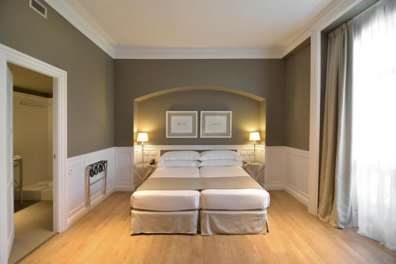 This spacious room has twin beds pushed together, with nightstands in an alcove. There is a luggage rack on the wall.