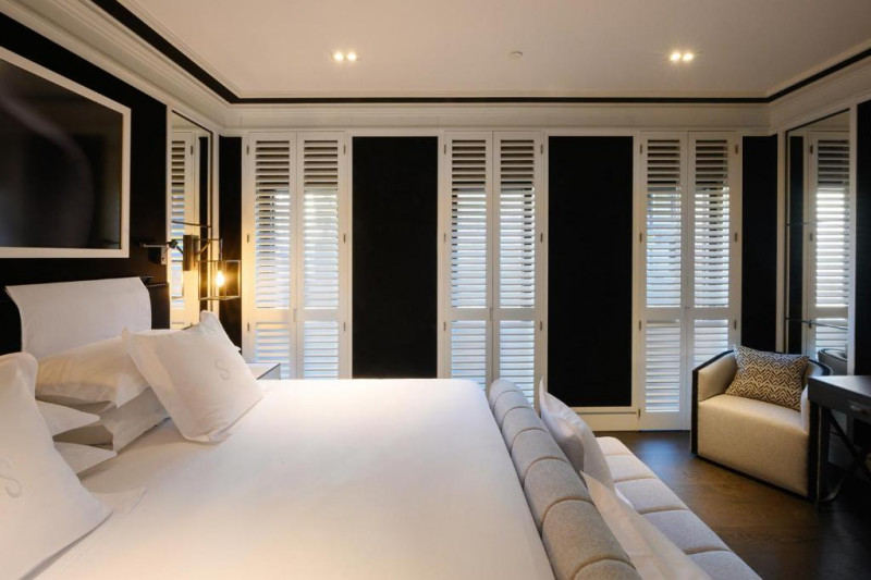 This room has a double king-sized bed with nightstands. There is a plush bed bench and an armchair.