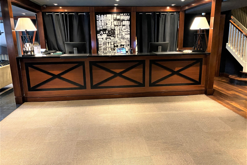 The spacious reception area has a high check-in desk. There is a flight of stairs leading to another floor.