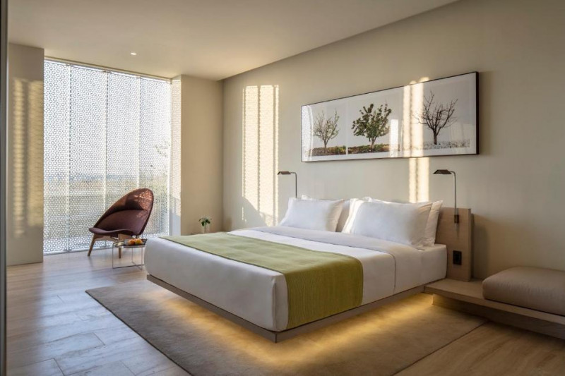 The spacious room has 1 king-sized bed with incorporated reading lamps. There is a high-back chair and a low coffee table.
