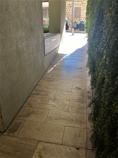 There is a narrow alley leading to the sidewalk.
