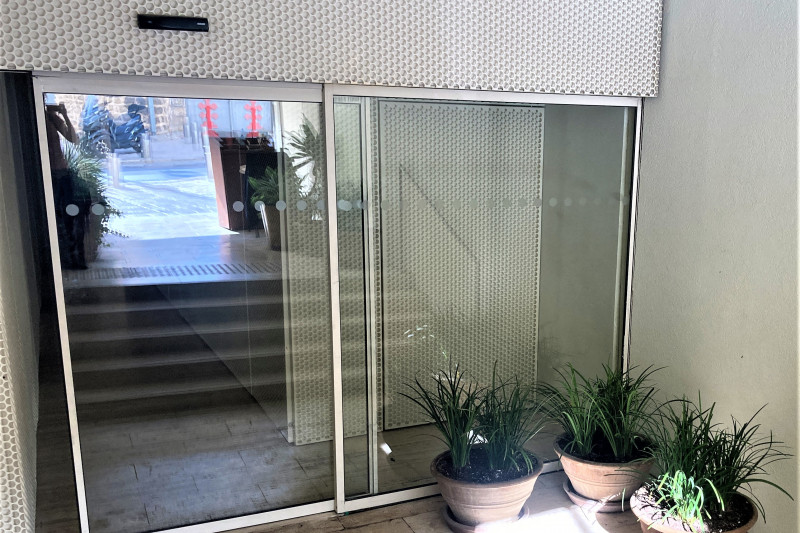 There are 5 steps with a handrail leading down to a sliding, glass door.