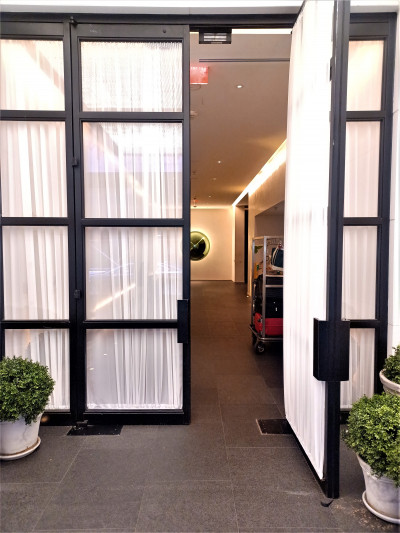 The tall glass door leads from the sidewalk into a spacious lobby.