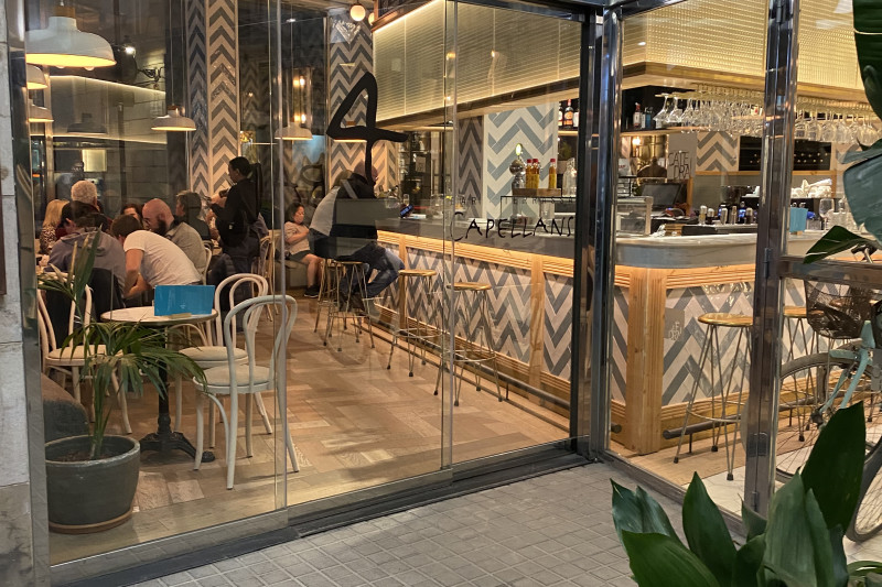 Access to Bar Capellans is through 2 glass sliding doors. The bar counter is lined with high bar stools.