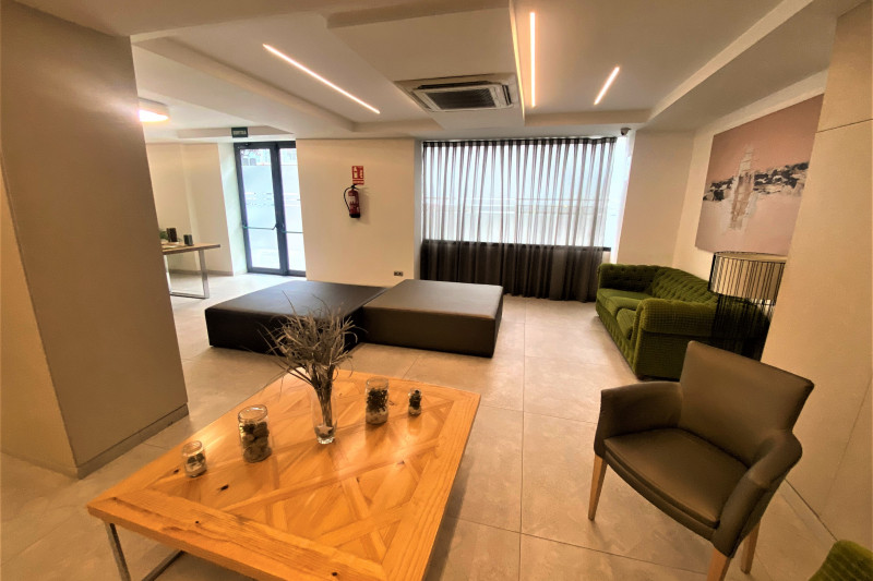 This spacious seating area has a sofa, an armchair, a low table and 2 big pouffes in the center of the room.
